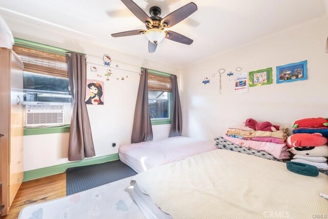 bedroom featuring ceiling fan, cooling unit, and hardwood / wood-style floors