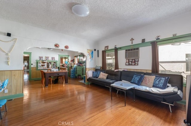 living room with hardwood / wood-style flooring, an AC wall unit, wooden walls, and a textured ceiling