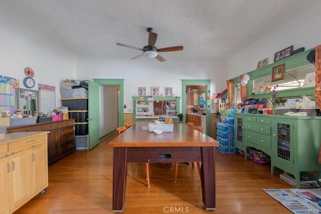 home office with ceiling fan, light hardwood / wood-style floors, and a textured ceiling