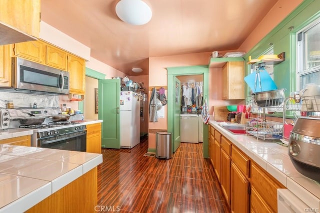 kitchen featuring washer / clothes dryer, white appliances, tile counters, and tasteful backsplash