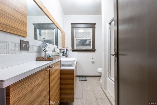 full bathroom featuring backsplash, toilet, enclosed tub / shower combo, and vanity