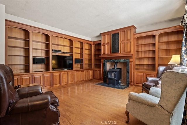 living room featuring light hardwood / wood-style flooring, a textured ceiling, and a wood stove