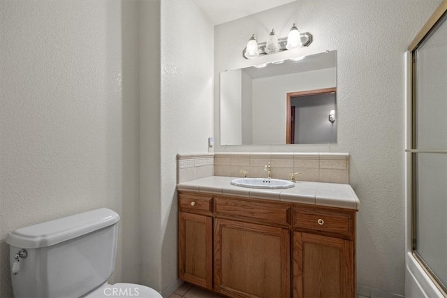 full bathroom featuring toilet, combined bath / shower with glass door, and vanity