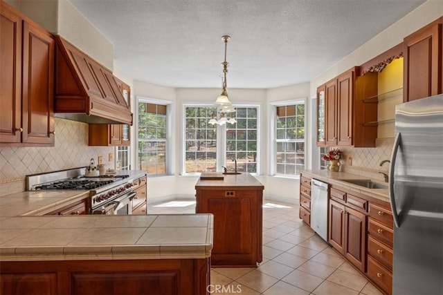 kitchen with light tile patterned floors, backsplash, a kitchen island, sink, and stainless steel appliances