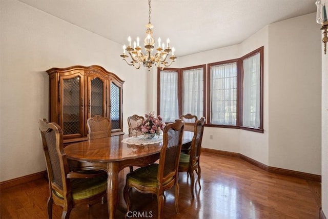 dining space with dark wood-type flooring and an inviting chandelier