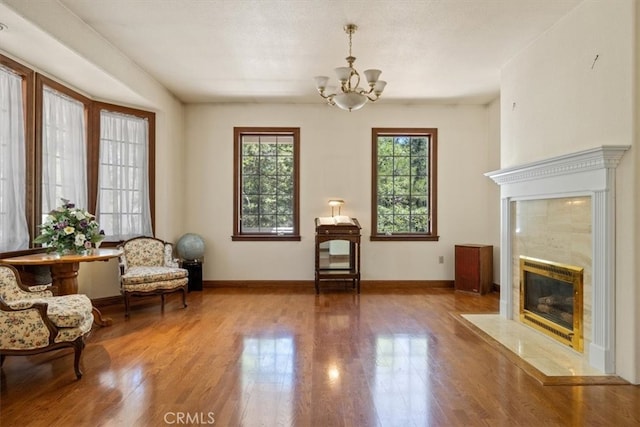 sitting room with wood-type flooring, an inviting chandelier, and a fireplace