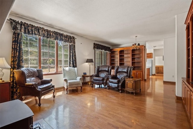 living room with an inviting chandelier, a textured ceiling, and light hardwood / wood-style floors