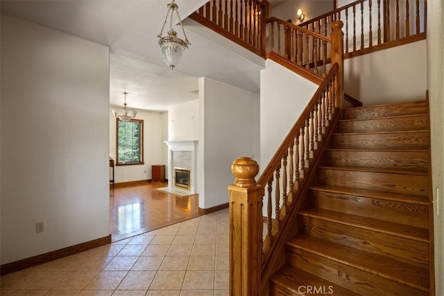 stairs featuring a notable chandelier, a textured ceiling, and tile patterned floors