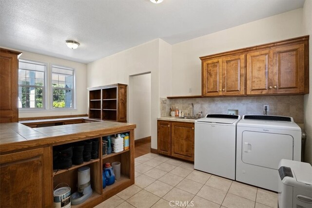 washroom featuring sink, light tile patterned floors, cabinets, and washing machine and clothes dryer