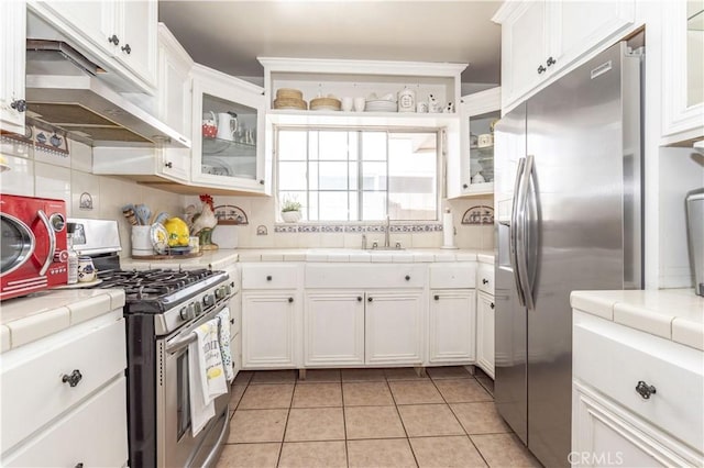 kitchen featuring appliances with stainless steel finishes, white cabinets, and tile counters