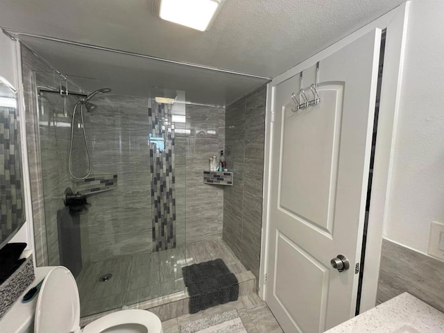 bathroom featuring toilet, a textured ceiling, and tiled shower