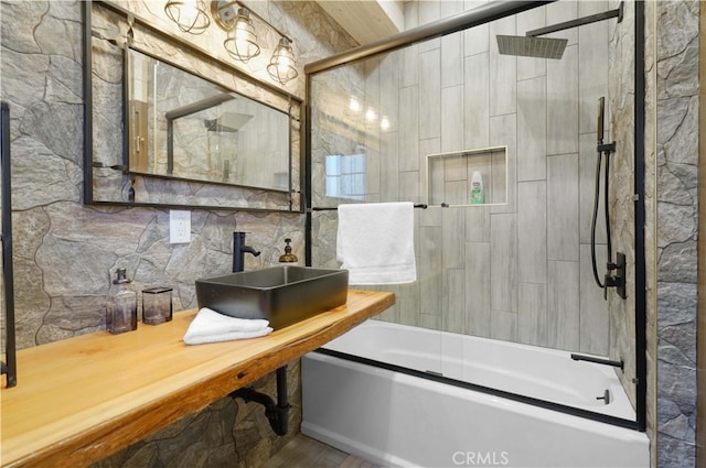 bathroom featuring sink, tile walls, and combined bath / shower with glass door