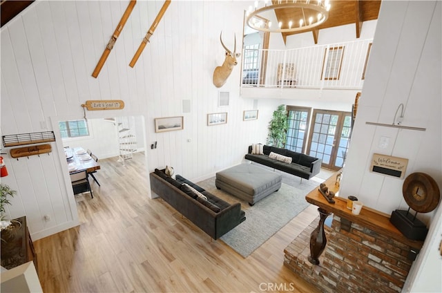 living room featuring light hardwood / wood-style floors, a high ceiling, and an inviting chandelier