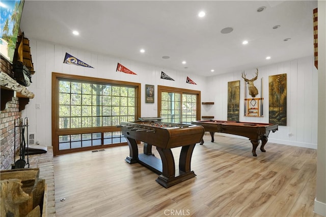 game room featuring pool table, a healthy amount of sunlight, light hardwood / wood-style floors, and a brick fireplace