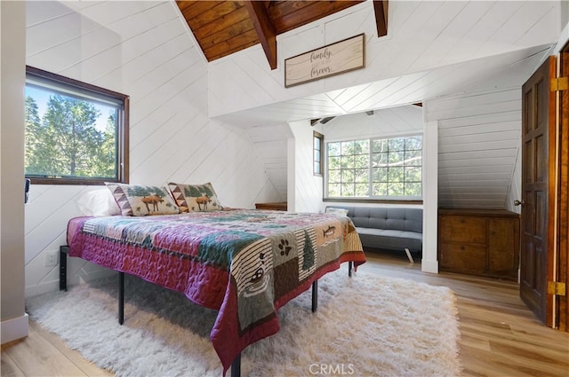 bedroom with wood walls, light hardwood / wood-style floors, and multiple windows