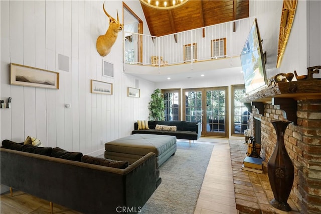 living room featuring wooden walls, high vaulted ceiling, a fireplace, wooden ceiling, and light wood-type flooring