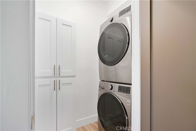 washroom featuring light hardwood / wood-style flooring and stacked washer / drying machine