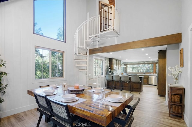 dining room with light hardwood / wood-style flooring and a high ceiling