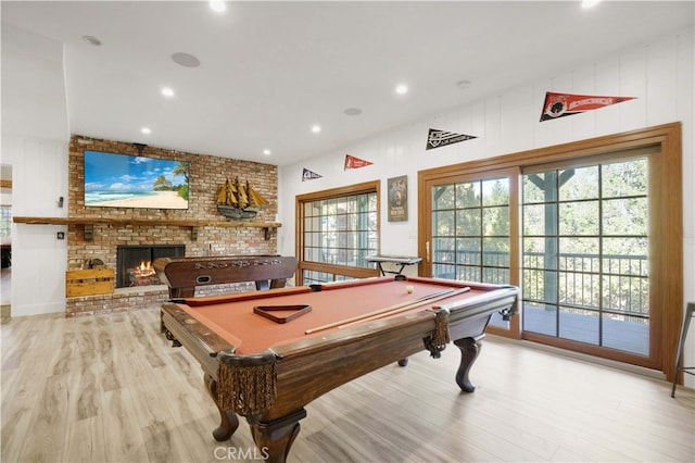 game room featuring light hardwood / wood-style flooring, vaulted ceiling, a fireplace, and billiards