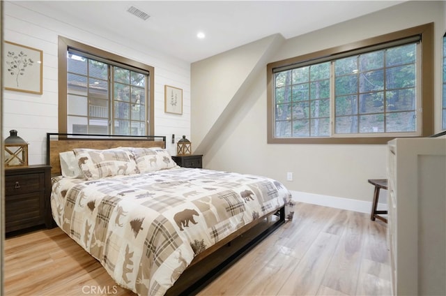 bedroom featuring wooden walls and light hardwood / wood-style floors