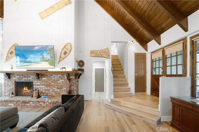 living room with wood ceiling, high vaulted ceiling, a fireplace, light wood-type flooring, and beam ceiling