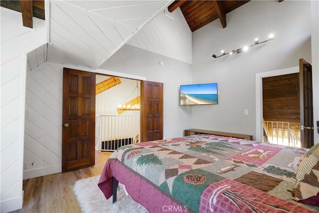 bedroom with wooden ceiling, wood walls, lofted ceiling with beams, and light hardwood / wood-style flooring