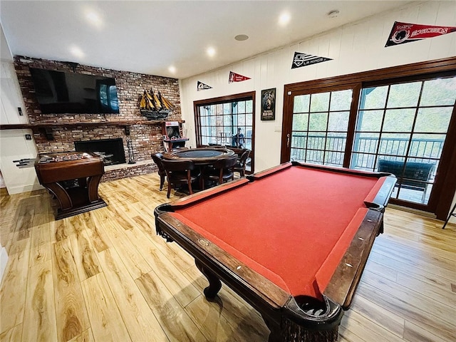 game room featuring wood-type flooring, billiards, and a brick fireplace