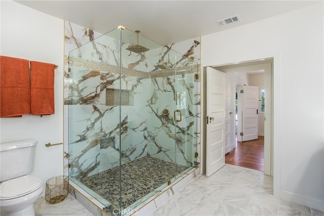 bathroom with wood-type flooring, a shower with shower door, and toilet