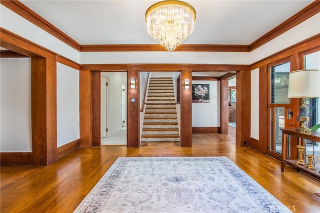 foyer entrance featuring a notable chandelier, crown molding, and hardwood / wood-style floors