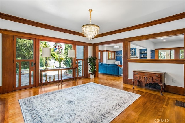 sitting room with ornamental molding, a notable chandelier, and hardwood / wood-style floors