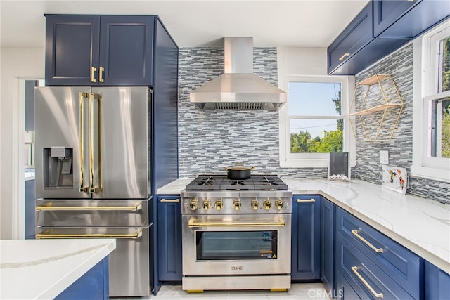 kitchen featuring premium appliances, wall chimney exhaust hood, backsplash, and a wealth of natural light