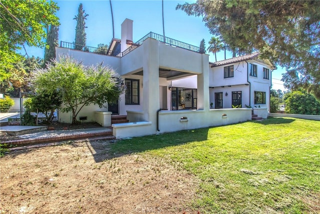 back of house featuring a balcony and a yard