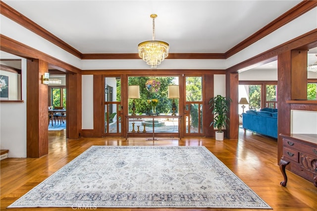 interior space featuring a notable chandelier, light wood-type flooring, and ornamental molding