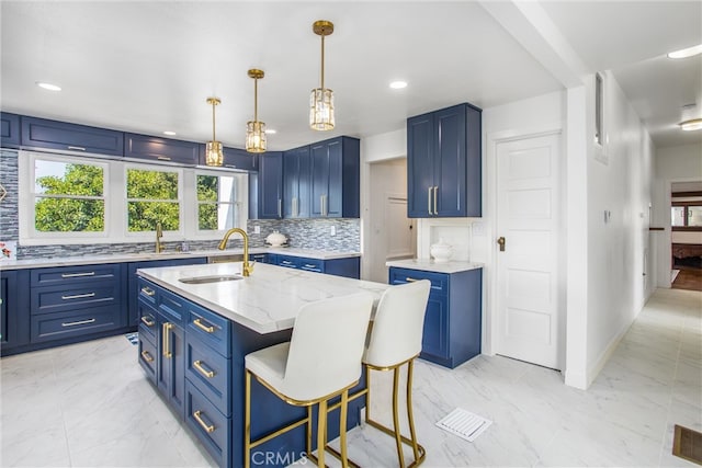 kitchen with blue cabinets, a center island with sink, sink, and tasteful backsplash