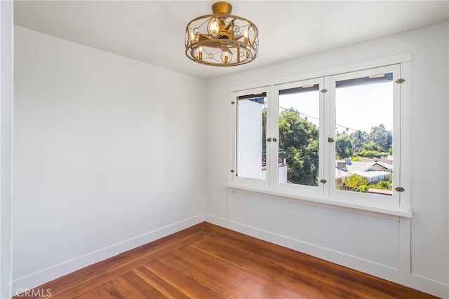 spare room featuring a notable chandelier and hardwood / wood-style flooring