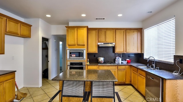 kitchen featuring light tile patterned flooring, sink, a kitchen island, backsplash, and stainless steel appliances