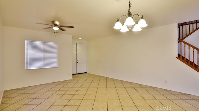 empty room featuring ceiling fan with notable chandelier and light tile patterned floors