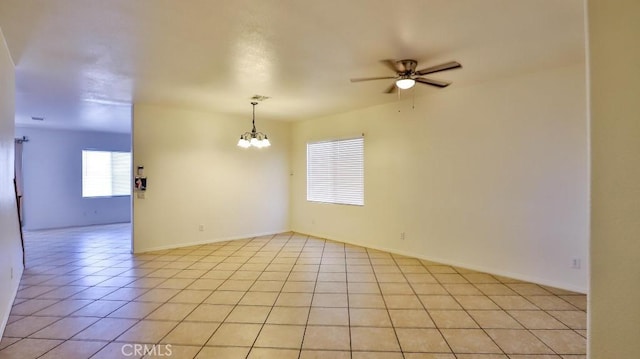 spare room with visible vents, ceiling fan with notable chandelier, baseboards, and light tile patterned flooring