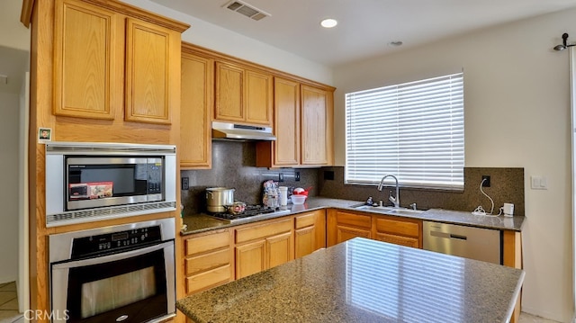 kitchen with dark stone counters, backsplash, sink, and stainless steel appliances