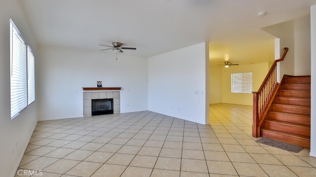 unfurnished living room with ceiling fan, light tile patterned floors, and a tile fireplace