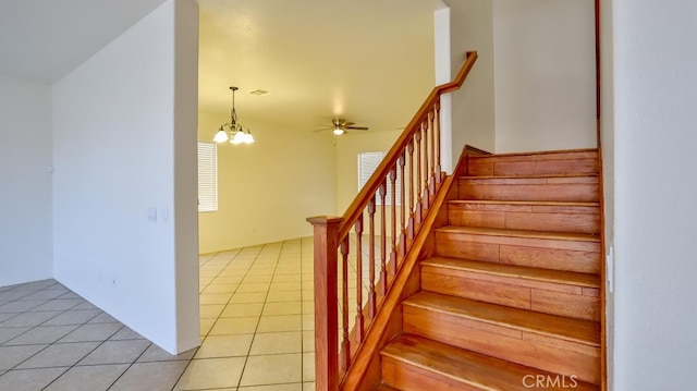 stairs featuring ceiling fan with notable chandelier and tile patterned flooring