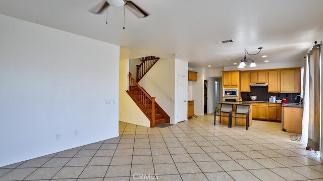 kitchen featuring ceiling fan with notable chandelier, stainless steel appliances, light tile patterned floors, and tasteful backsplash