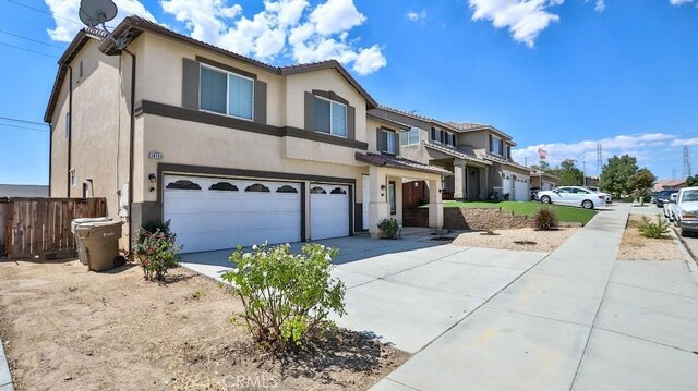 view of front of property with concrete driveway, stucco siding, an attached garage, and a tile roof
