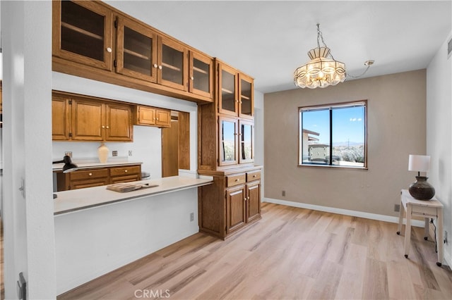 kitchen featuring hanging light fixtures, light hardwood / wood-style floors, and kitchen peninsula