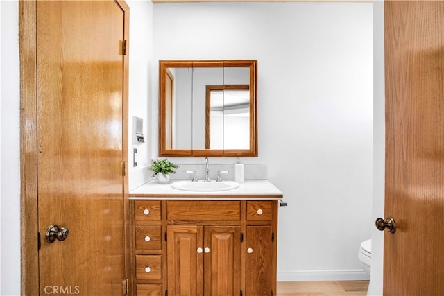 bathroom with wood-type flooring, vanity, and toilet