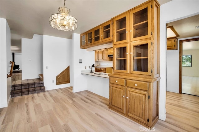 kitchen featuring pendant lighting, a notable chandelier, light hardwood / wood-style floors, and sink