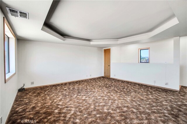 carpeted empty room featuring a tray ceiling