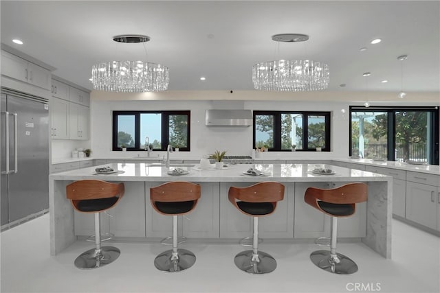 kitchen featuring a breakfast bar, stainless steel built in fridge, gray cabinets, decorative light fixtures, and a wall unit AC