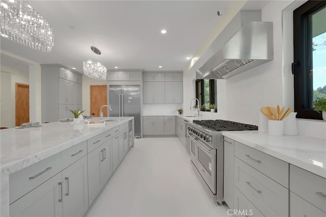 kitchen with hanging light fixtures, gray cabinets, high end appliances, and exhaust hood