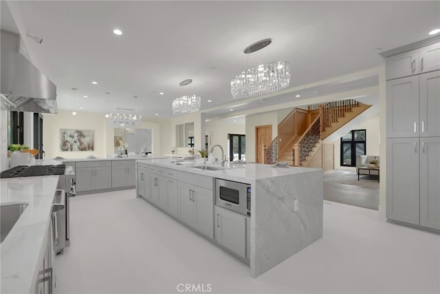 kitchen with sink, decorative light fixtures, stainless steel microwave, a large island, and range hood